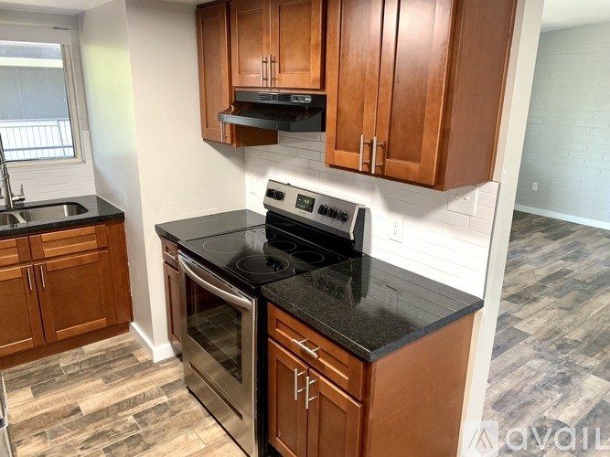 A kitchen with wooden cabinets and black countertops.
