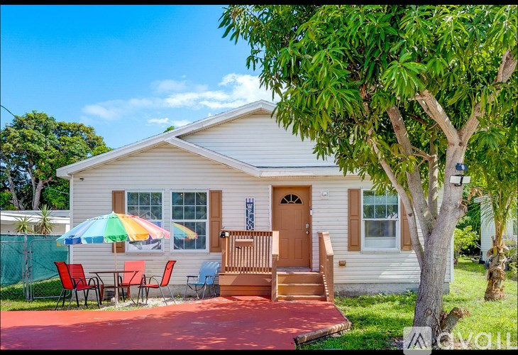 A house with a red umbrella and a red table and chairs.