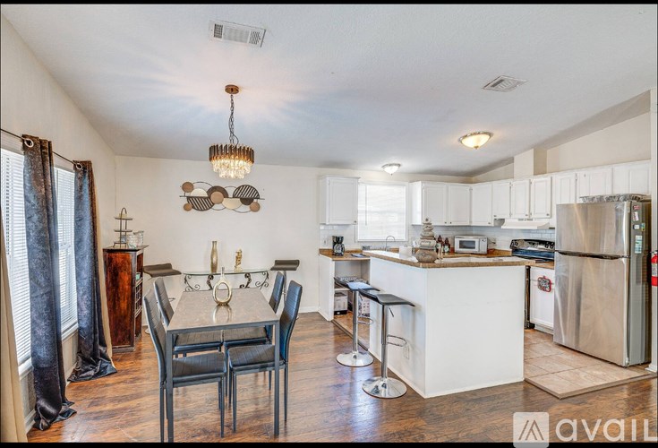 A kitchen with a dining table and chairs in the foreground.