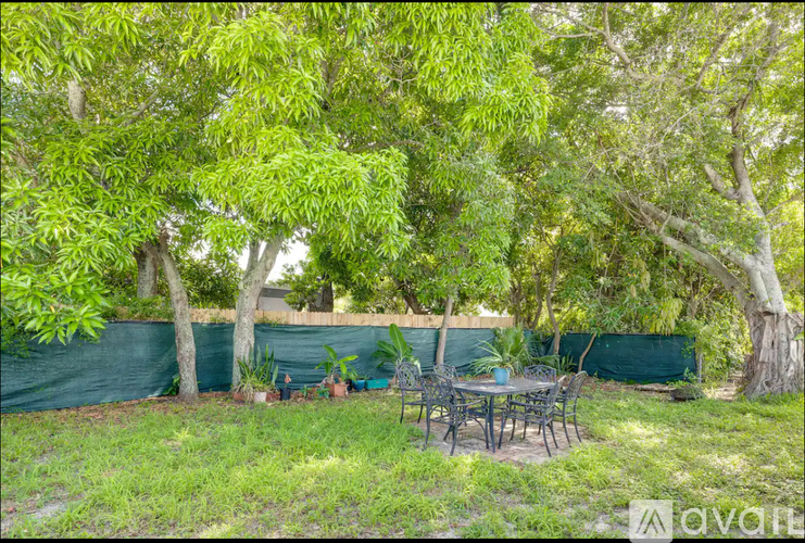 A backyard with a table and chairs surrounded by trees.