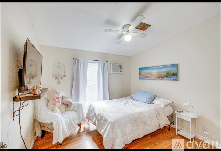 A bedroom with two beds, a ceiling fan, and a painting on the wall.