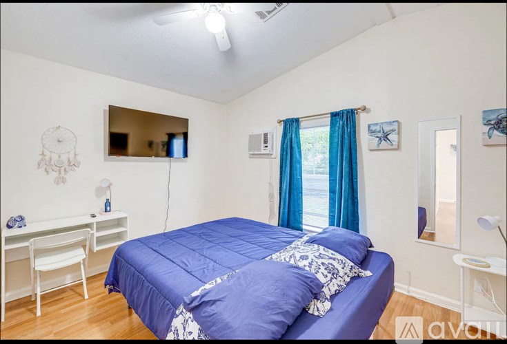 A bedroom with a blue bedspread and a white chair.