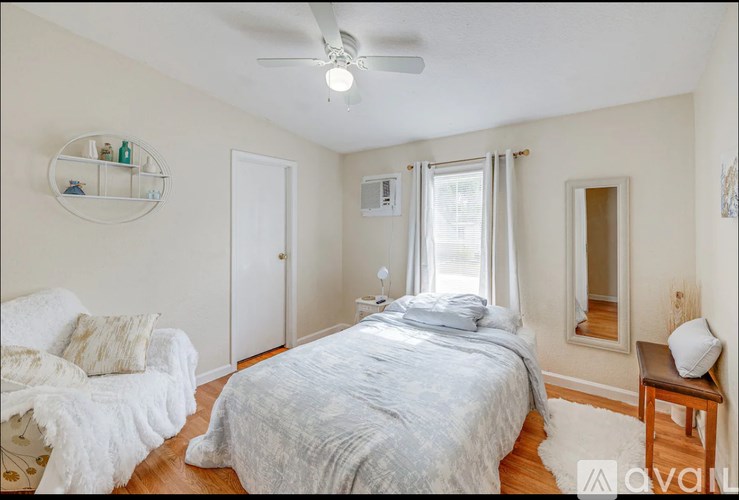 A bedroom with a bed, chair, and window.