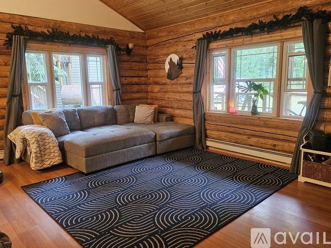 A living room with a grey couch and a black and white patterned rug.