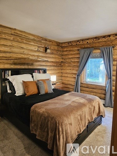 A bedroom with a large bed and wooden walls.