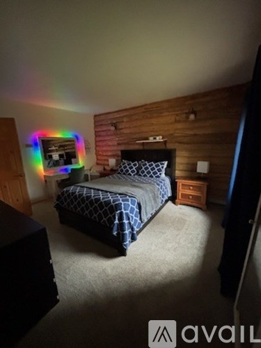 A bedroom with a bed, dresser, and a wooden wall.