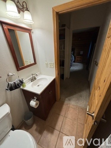 A bathroom with a toilet, sink, mirror and wooden door.