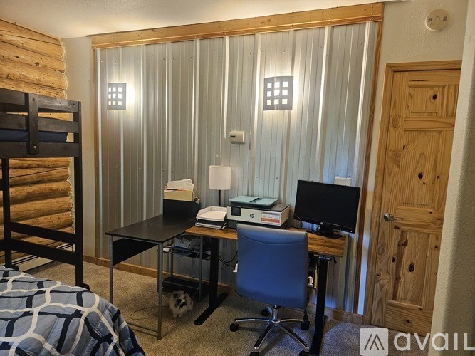 A room with a bed, desk, chair, and a dog.
