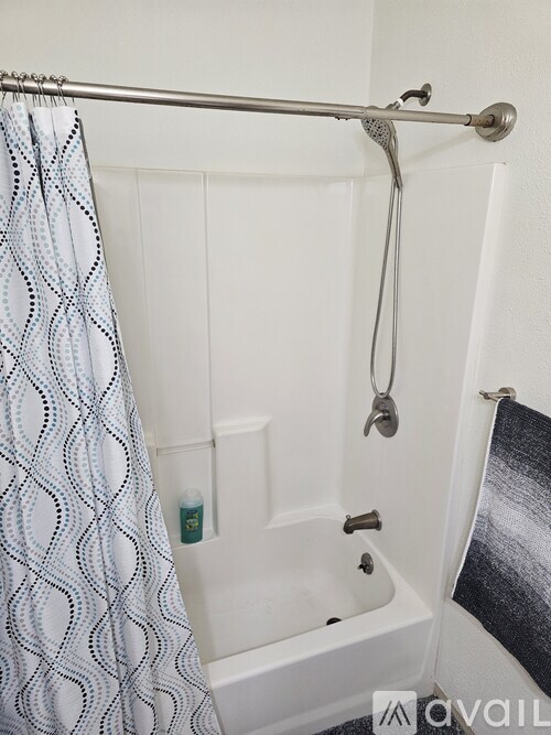 A white bathtub with a shower curtain and a shower head.