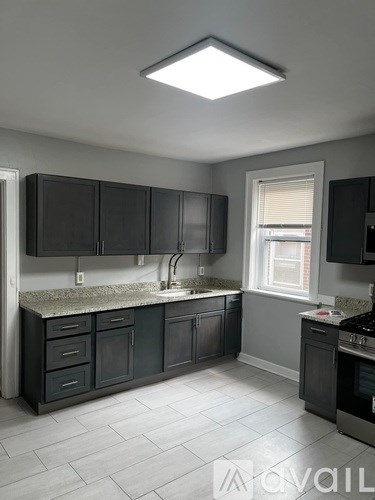 A kitchen with black cabinets and a marble countertop.