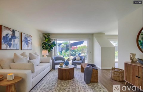 A living room with a white couch, a wooden coffee table, and a painting on the wall.