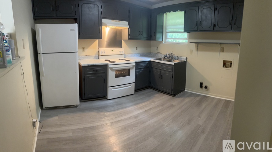 A kitchen with a white refrigerator, stainless steel oven, and grey cabinets.
