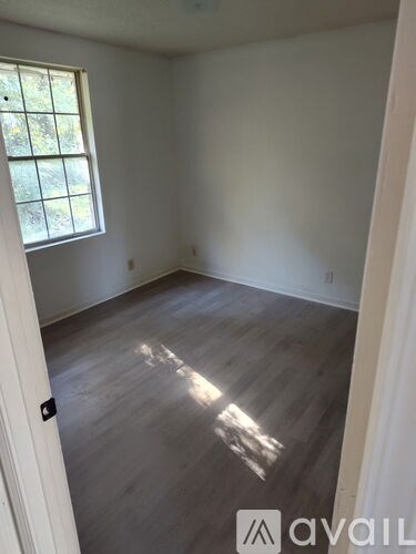 A room with a window and wooden flooring.