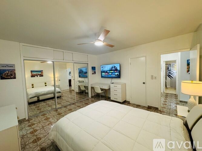 A bedroom with a large bed, a desk with a chair, and a television.