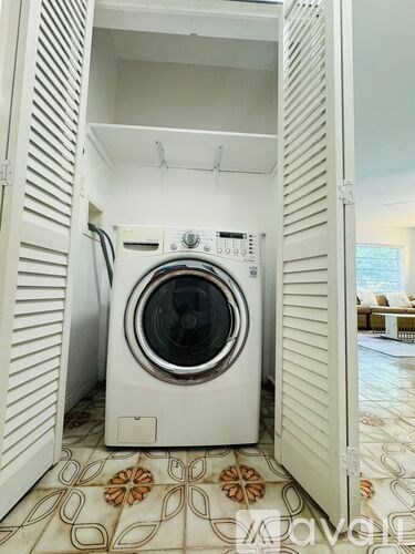 A white washing machine is in a white cabinet.