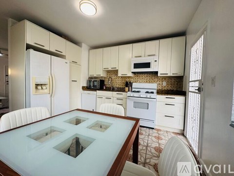 A kitchen with white cabinets and a glass table.