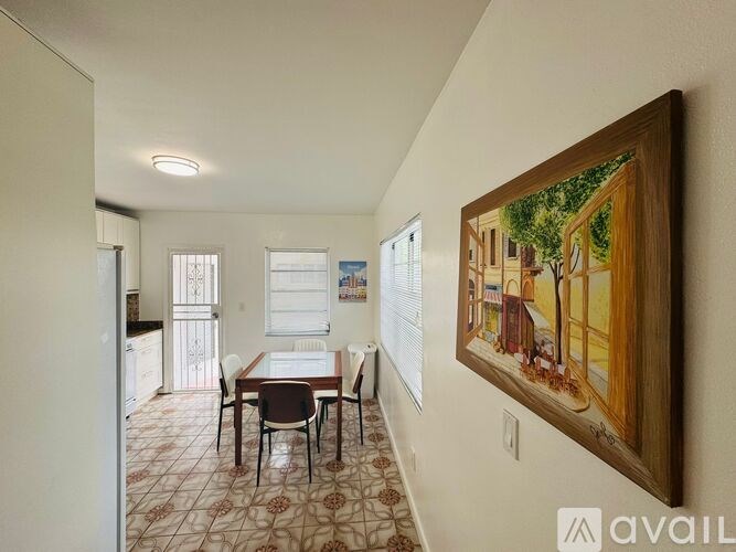 A dining room with a table and chairs and a painting on the wall.