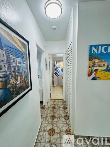 A hallway with a poster on the wall and a painting hanging on the wall.