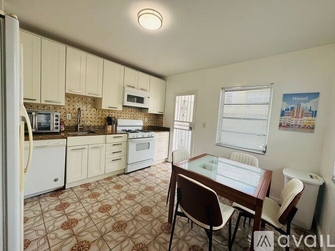 A kitchen with a refrigerator, microwave, oven, and sink.