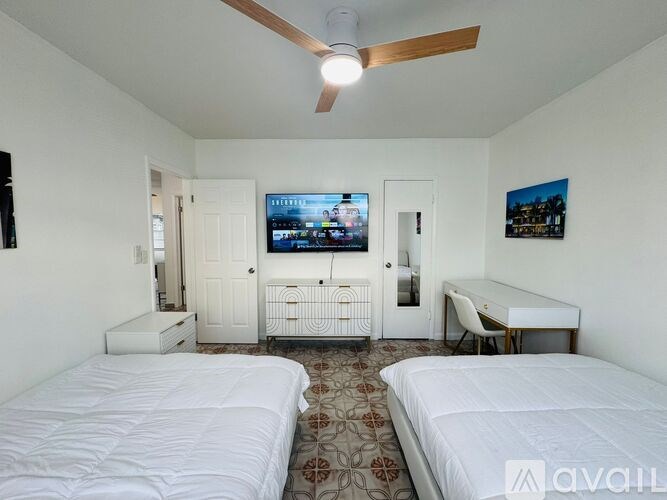 A bedroom with two beds, a desk, and a television.