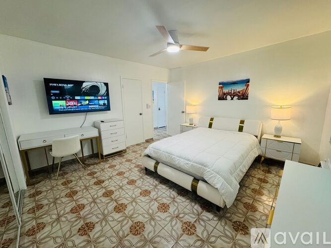 A bedroom with a bed, desk, and television.