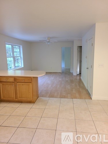 A kitchen with a counter and cabinets with a window above it.