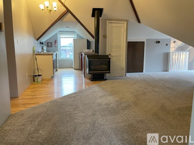 A living room with a fireplace and a grey carpet.