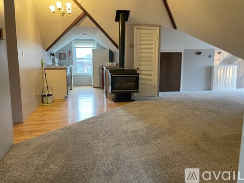 A living room with a fireplace and a grey carpet.