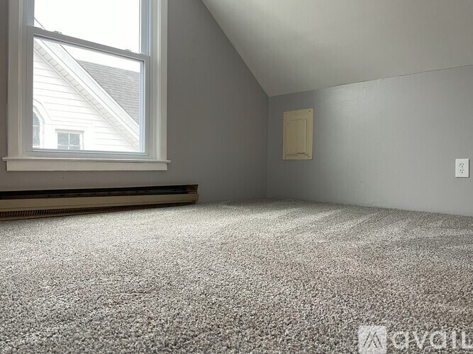 A room with a carpeted floor and a window.
