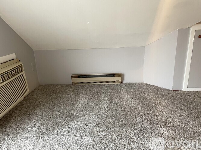 A room with a carpeted floor and a window with blinds.