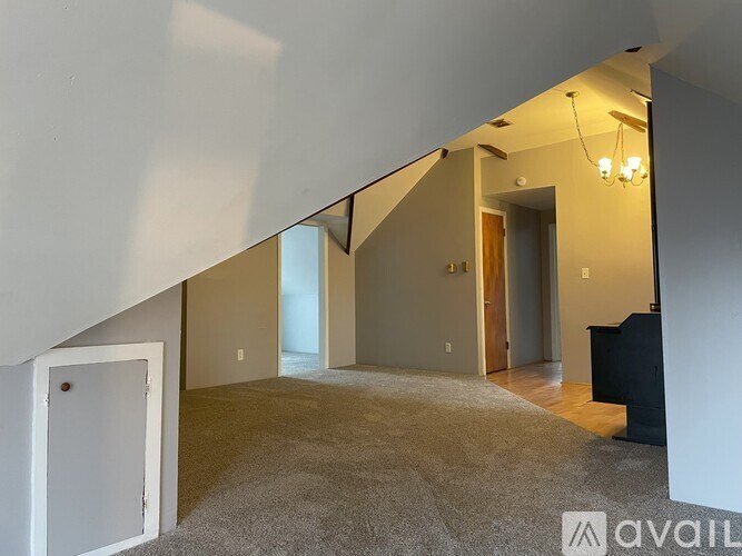 A room with a carpeted floor and a chandelier hanging from the ceiling.