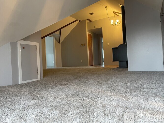 A room with a carpeted floor and a staircase.