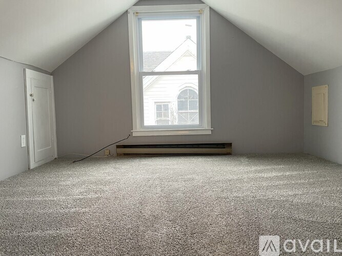 A room with a large window and carpeted floor.