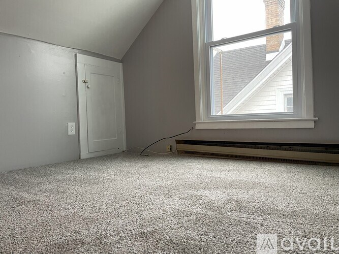 A room with a carpeted floor, a window, and a door.