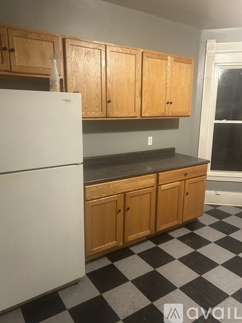 A kitchen with wooden cabinets and a black and white checkered floor.