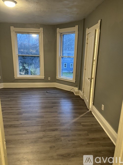 A room with wooden floors and two windows.