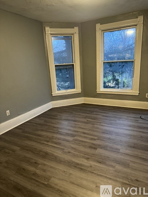 A room with two windows and wooden flooring.
