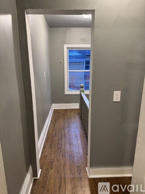 A hallway with wood flooring and a window.