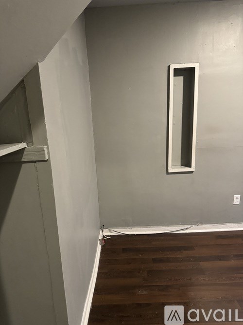 A hallway with a wooden floor and a white wall with a number 1 on it.