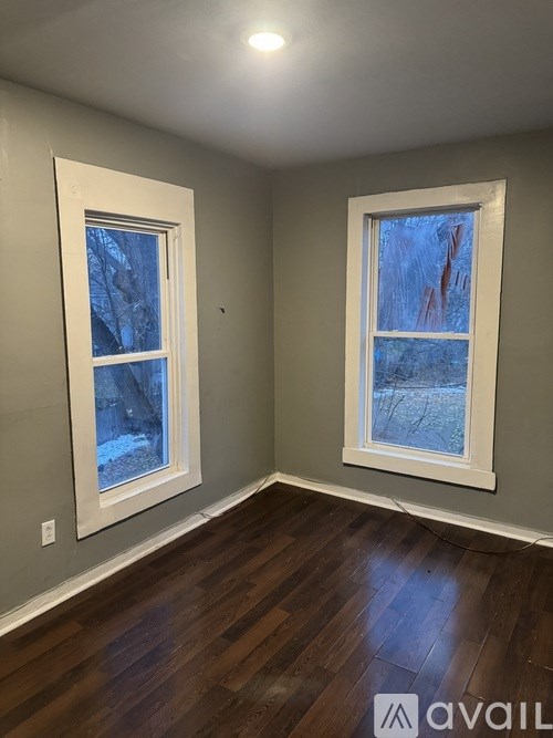 A room with two windows and wooden floors.