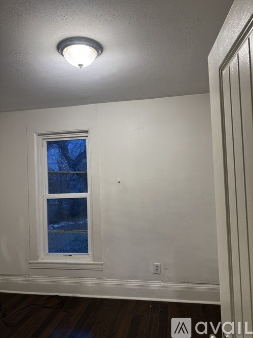 A white wall with a window and a light on.
