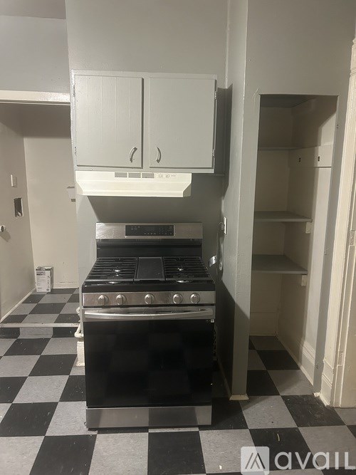 A black and white checkered floor with a stove and white cabinets above it.
