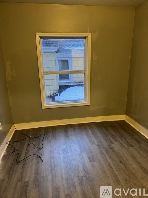 A room with a window and wooden flooring.