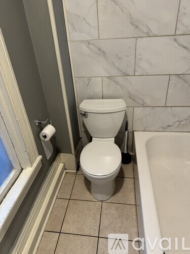 A white toilet in a bathroom with marble tiles.