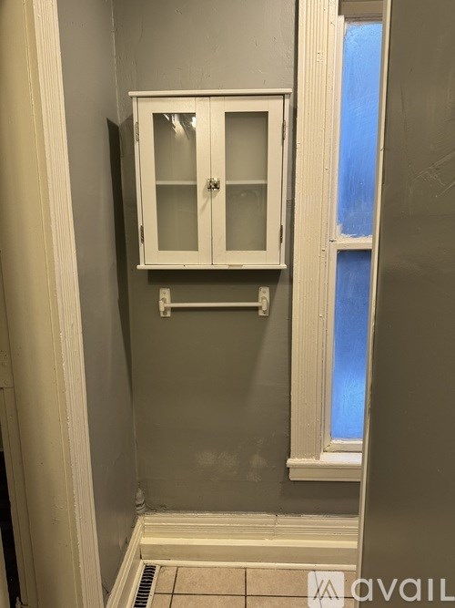 A bathroom with a cabinet above a tiled floor.