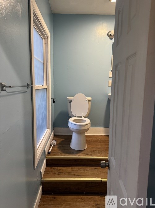 A white toilet in a blue bathroom with a white door.