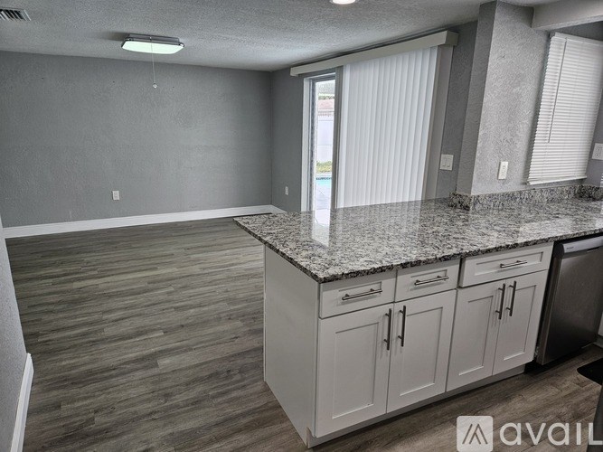 A kitchen with white cabinets and a granite countertop.