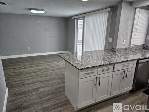 A kitchen with white cabinets and a granite countertop.