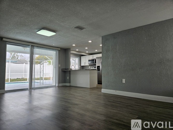 A spacious room with a kitchenette and sliding glass doors leading to a balcony.