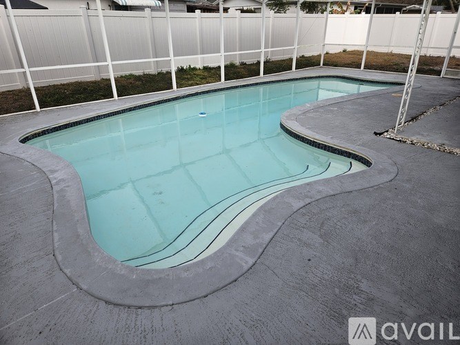 A small, kidney-shaped pool with a white fence in the background.